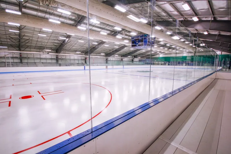 White dasherboards with blue kickplate along the length of an ice rink
