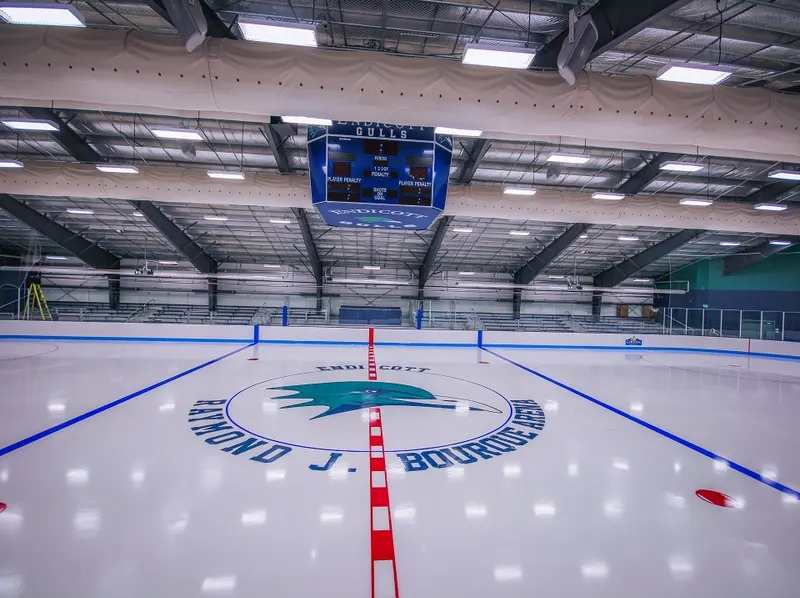 Zamboni resurfacing a community arena sheet with a painted logo at center ice
