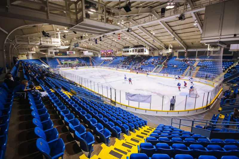 Indoor hockey arena with blue seating overlooking a freshly resurfaced ice sheet