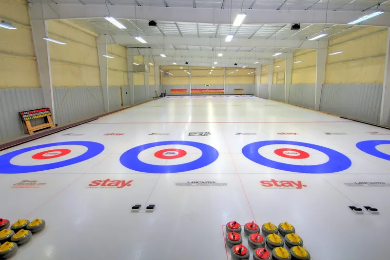 Curling sheets with painted houses and stones ready at the hack inside a dedicated curling facility