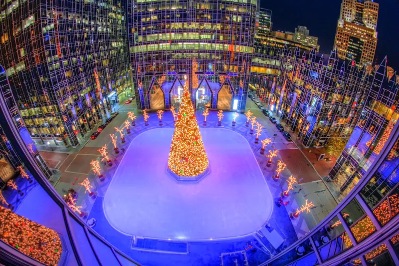 Aerial view of a holiday rink lit in purple around a tree
